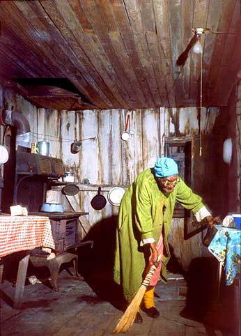Old woman sweeping shack